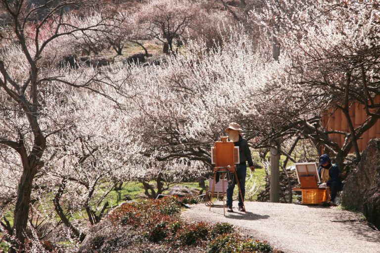 An artist painting outdoors among soft flowering trees in early spring — an impressionist scene in nature.