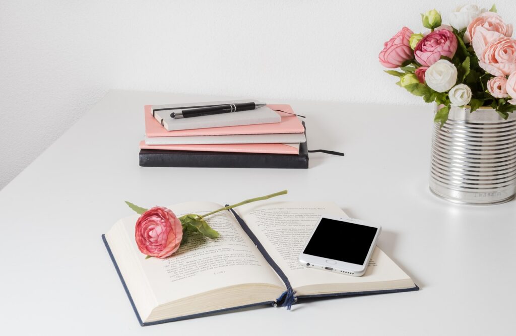 How to start a blog – flatlay with pink flowers, open notebook, and coffee cup on a white desk