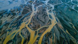 An abstract, aerial photo of a clear, organized river of thought flowing into a chaotic, branching delta, symbolizing the feeling of AI overwhelm