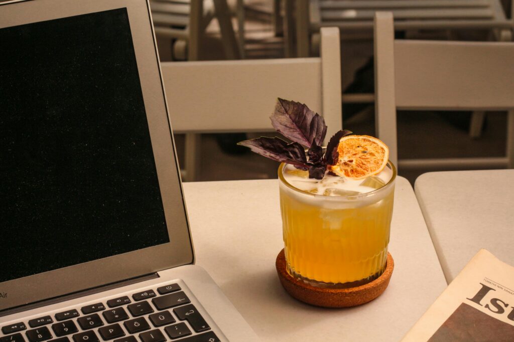 A laptop and cocktail on a patio table in warm light, symbolizing defining wins with AI through clarity, structure, and balance.