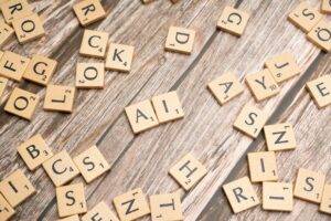 Scrabble tiles scattered across a wooden table with the letters A and I placed together in the center, representing AI prompt fluency and the art of structured language.