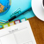 Open planner with to-do list, colorful tabs, pen, coffee cup, and globe — illustrating communicating with different learning styles
