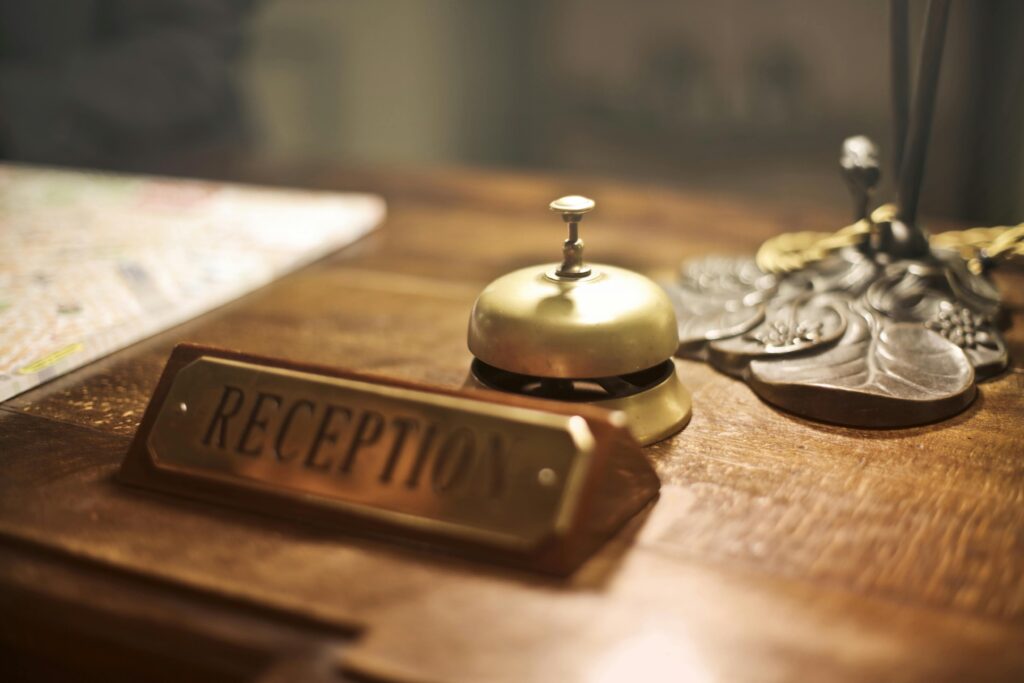 A brass hotel reception bell and sign on a wooden counter, symbolizing pre-boarding the brain through thoughtful planning, care, and readiness for travel.