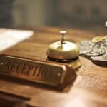 A brass hotel reception bell and sign on a wooden counter, symbolizing pre-boarding the brain through thoughtful planning, care, and readiness for travel.